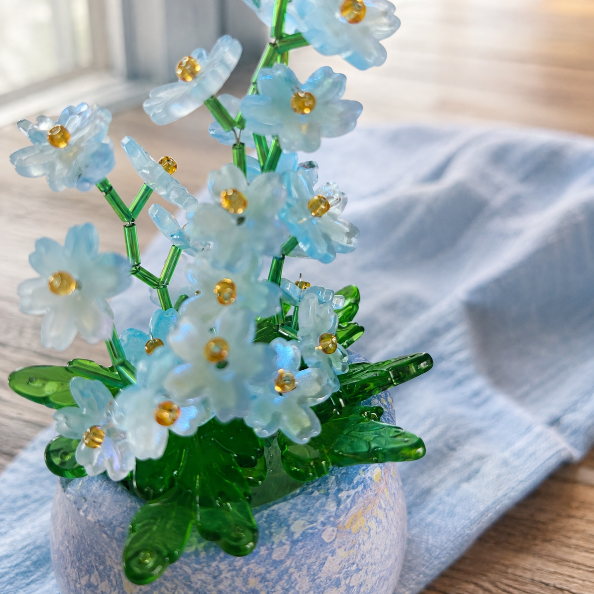 Close-up of blue beaded flowers and translucent green leaf beads