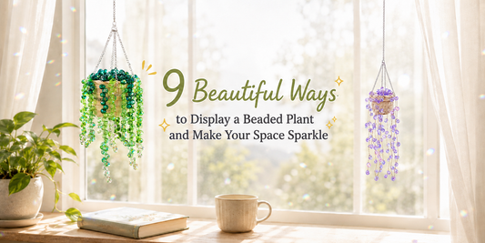 Green and purple handmade beaded hanging plants displayed beside a sunny window with faceted glass beads reflecting colorful light.