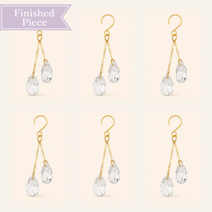 Six clear crystal plant vine suncatcher charms with gold-tone hooks arranged on a warm ivory background.