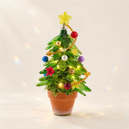 Light-up beaded Christmas tree with green glass leaves on a cream background