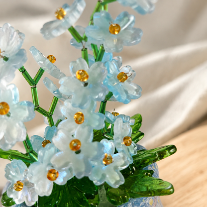 Close-up of translucent blue flower beads with gold centers and green stems
