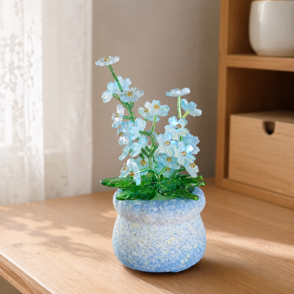 Blue forget-me-not beaded plant in a speckled blue pot on a sunlit wooden desk
