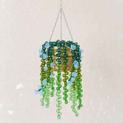 Cascading green beaded hanging plant with pale blue flower beads and a silver chain