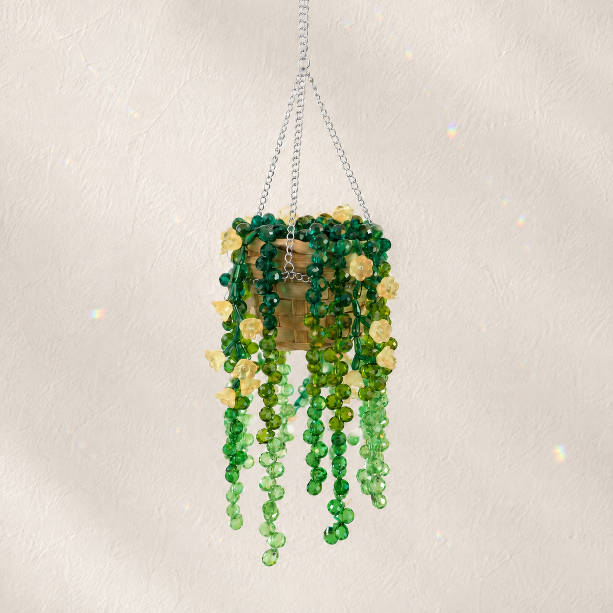 Cascading green beaded hanging plant with pale yellow flower beads and a silver chain