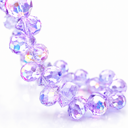 Close-up of translucent purple faceted teardrop glass beads reflecting rainbow light
