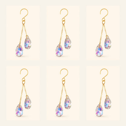 Six AB iridescent crystal plant vine suncatcher charms with gold-tone hooks arranged on a warm ivory background.