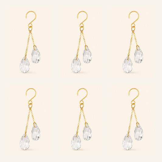 Six clear crystal plant vine suncatcher charms with gold-tone hooks arranged on a warm ivory background.